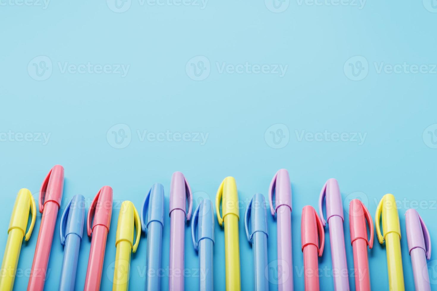 Multi-colored pens on a blue background with free space. photo