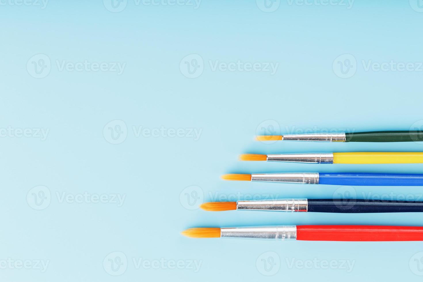 Brushes of different colors for drawing, creativity and art on a blue background. photo