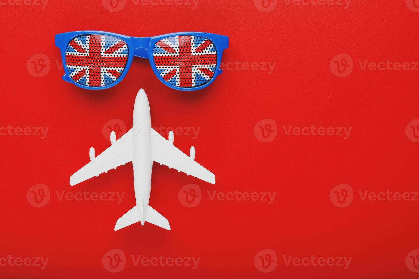 White airplane and sunglasses with the flag of the United Kingdom on a red background. Travel to England. photo