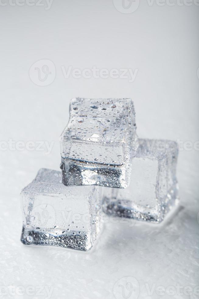 cubos de hielo en forma de pirámide con gotas de agua cerca - en macro sobre un fondo blanco. foto