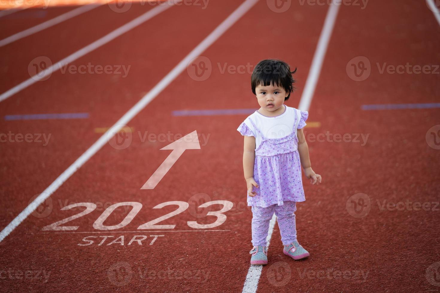 Asian baby running start into the new year 2023. Start up of runner girl running on race training lane race track go to Goal of Success. People running as part of Number 2023. Sport health care. photo