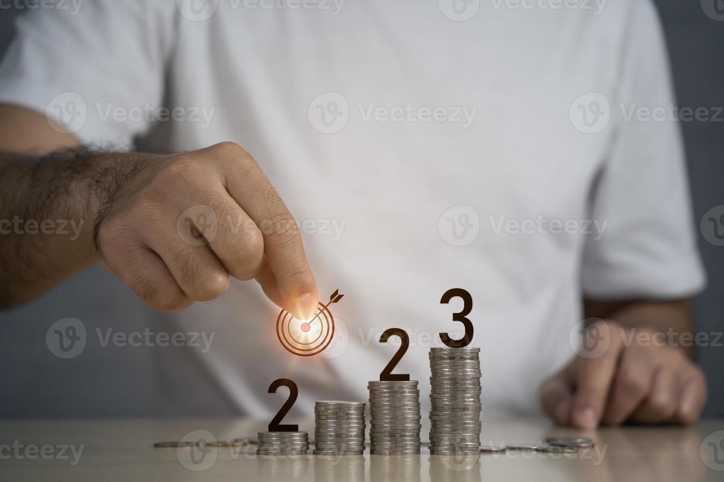 Hand business man target dart goal 2023 on top rows stack of coins with copy space. Saving money and financial tax payment banking plan for new year concept for investment future in new year 2023. photo