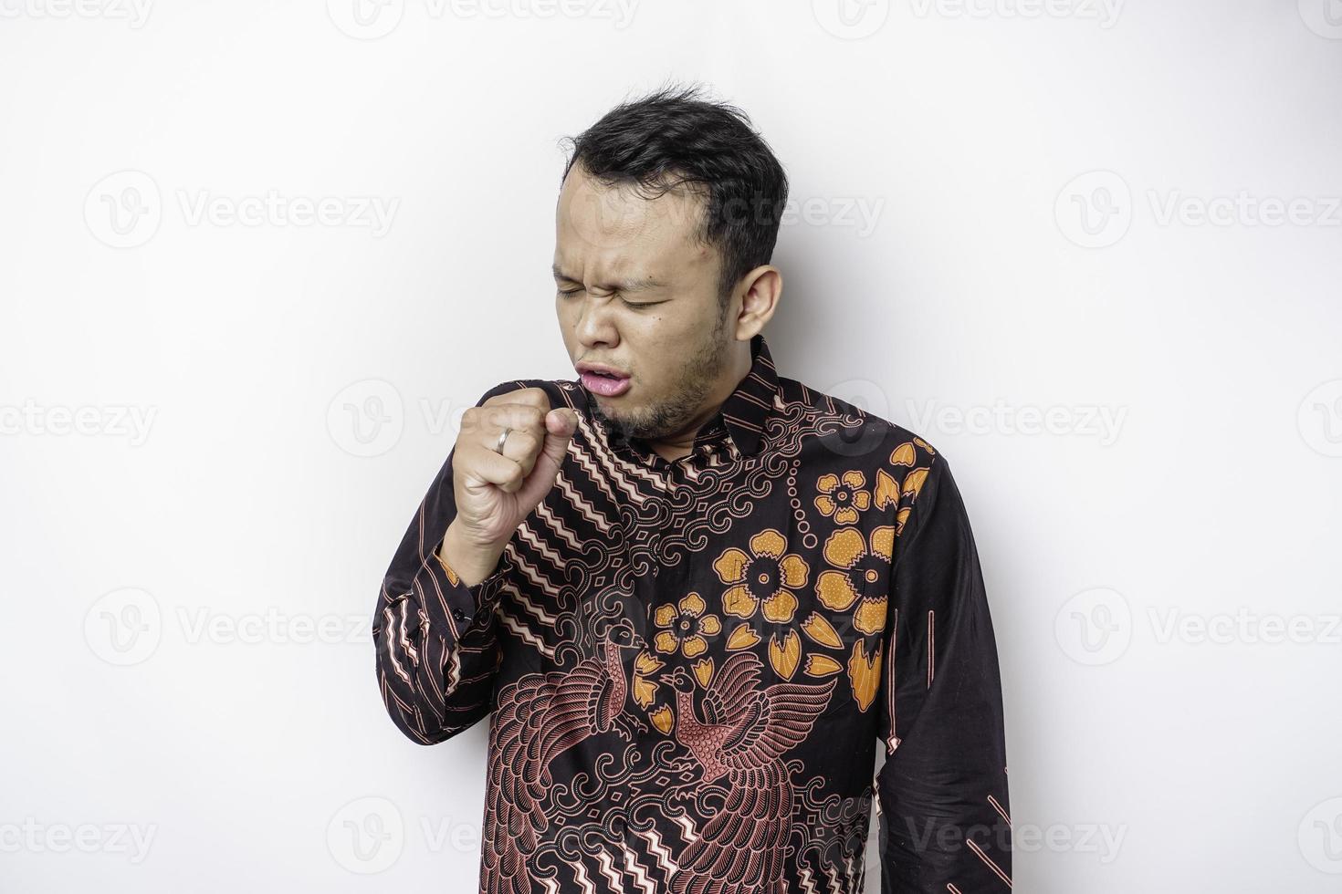 Sick Asian man wearing batik shirt is flu and cough. Illness, influenza, pain concept. Healthcare and Corona Concepts. photo