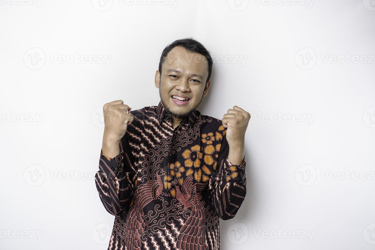 un joven asiático con una expresión feliz y exitosa que usa pantalones batik aislado de fondo blanco foto