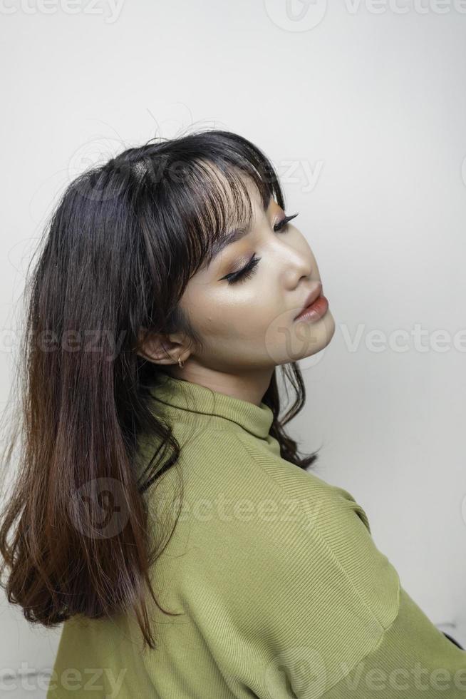 una cara alegre de belleza de una joven modelo asiática con top verde. tratamiento facial de belleza para el cuidado de la piel, spa, concepto de salud femenina. foto
