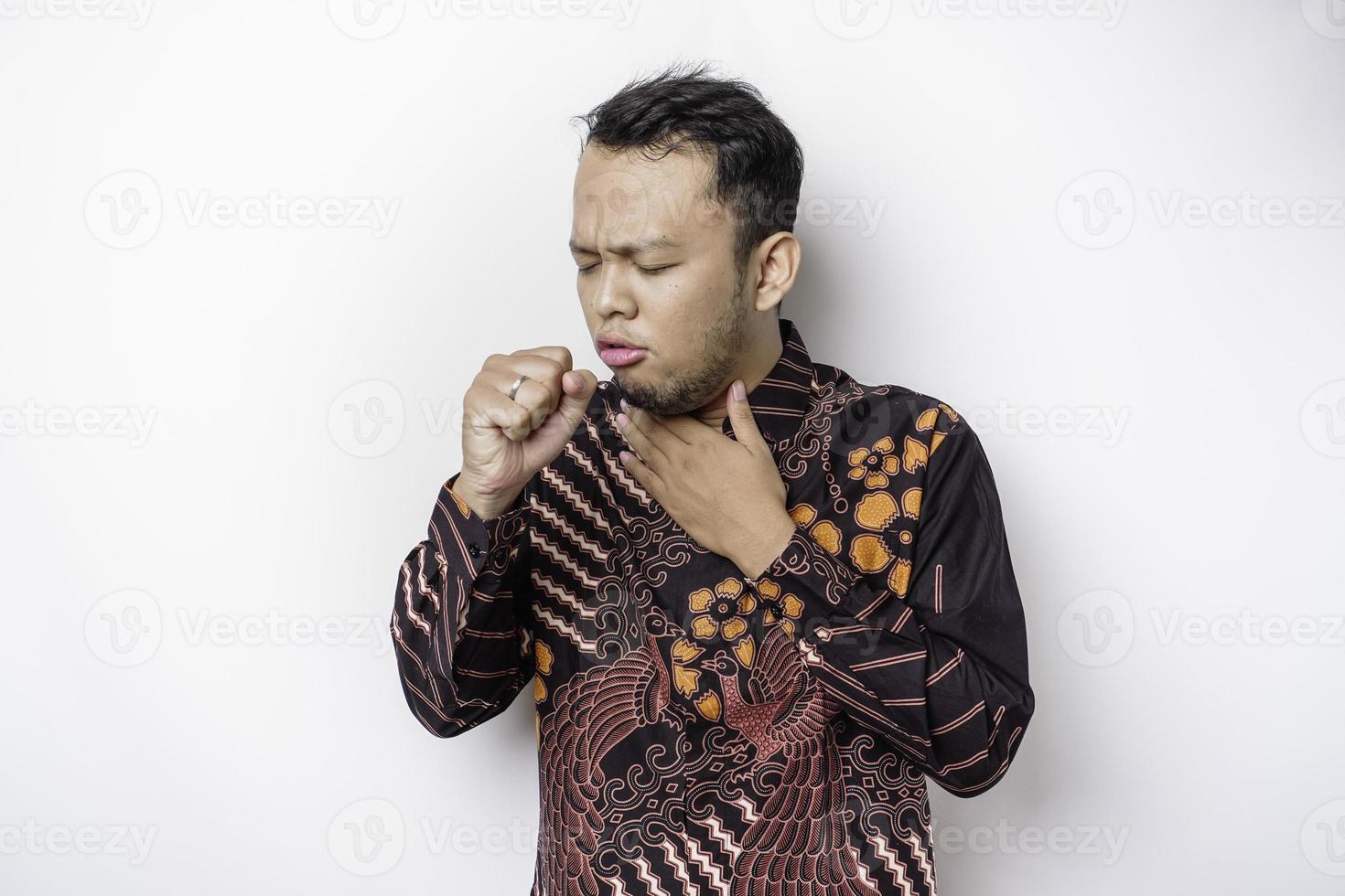 Sick Asian man wearing batik shirt is flu and cough. Illness, influenza, pain concept. Healthcare and Corona Concepts. photo