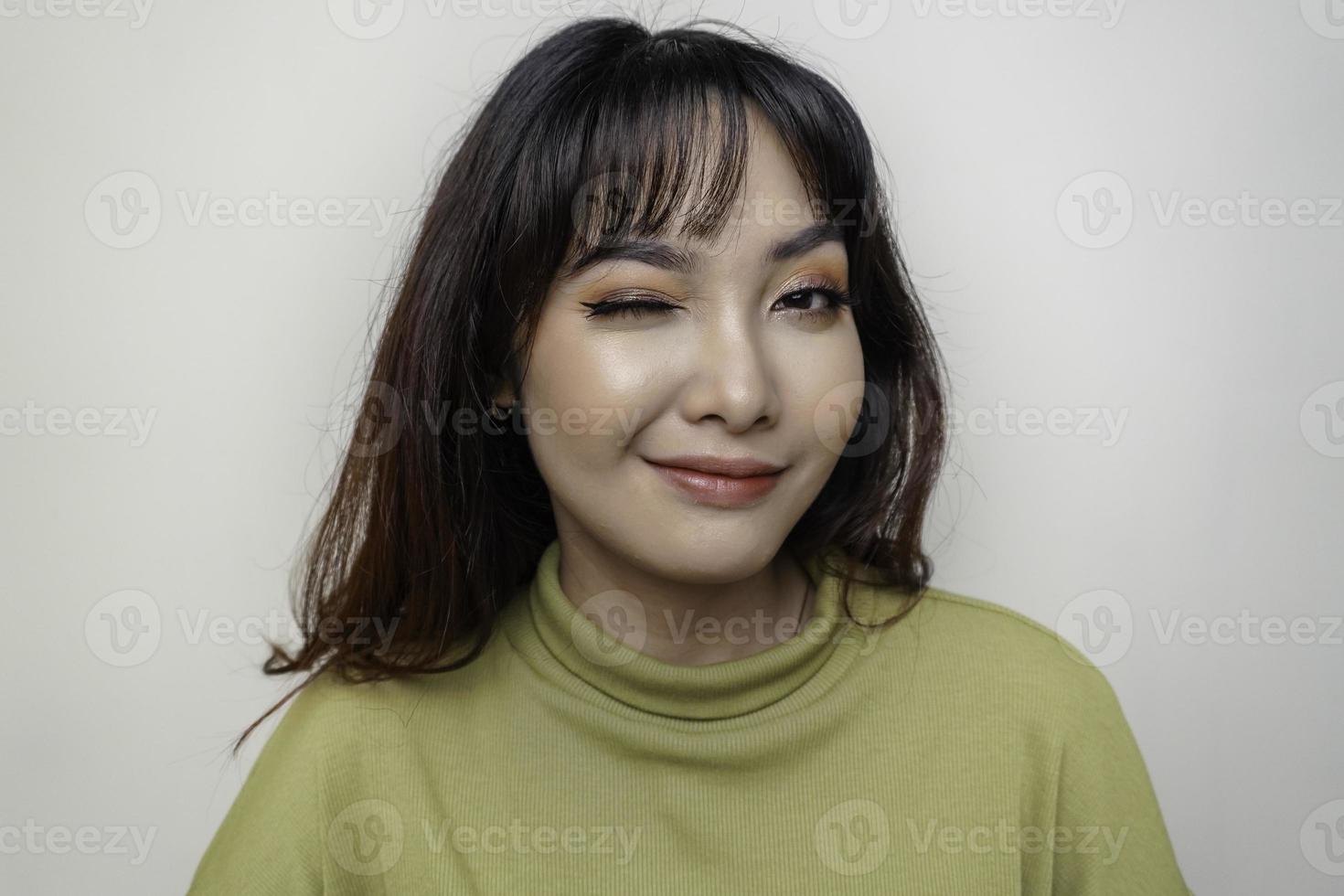 una cara alegre de belleza de una joven modelo asiática con top verde. tratamiento facial de belleza para el cuidado de la piel, spa, concepto de salud femenina. foto