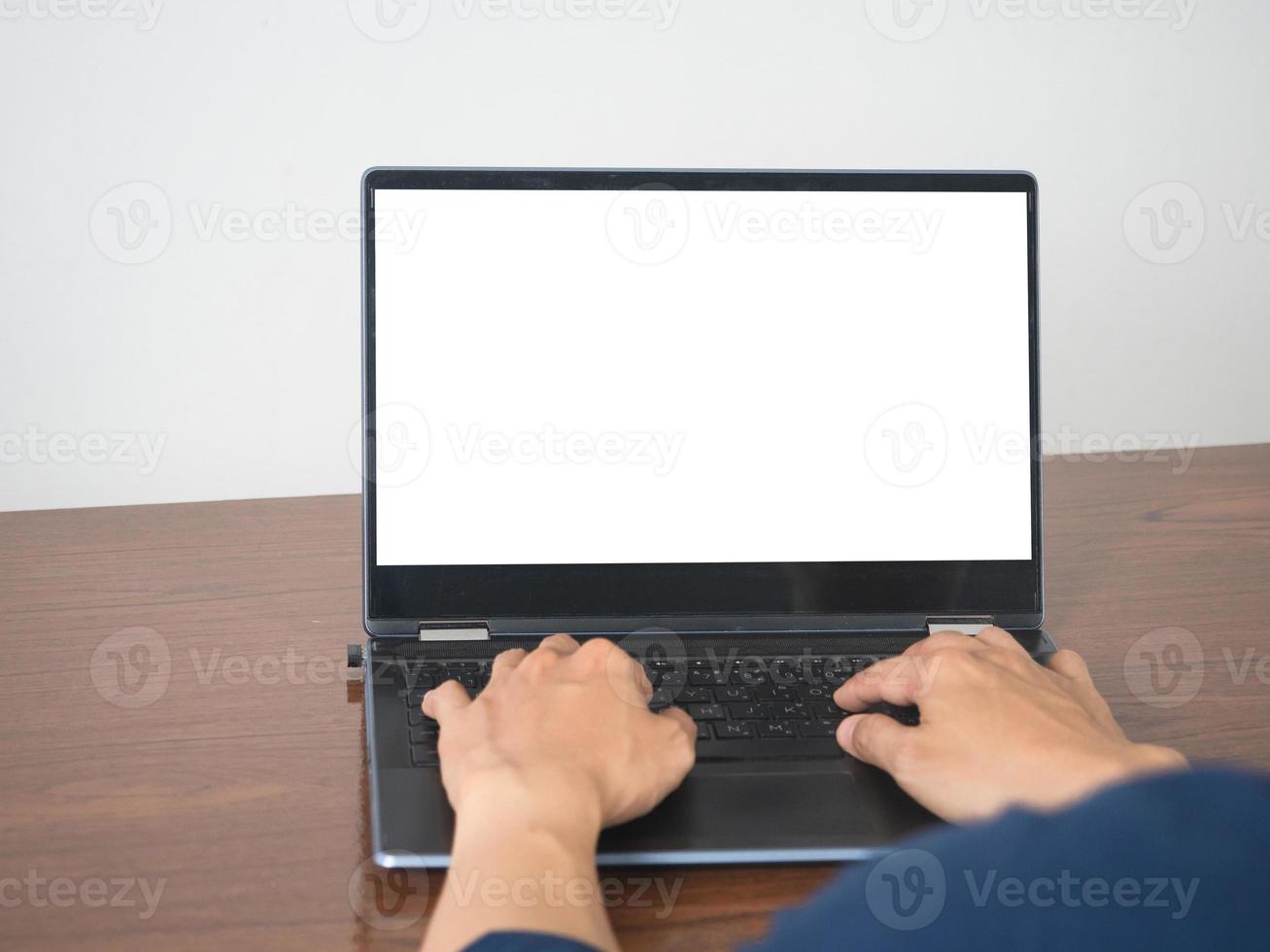 Man hands using keyboard of laptop mockup white screen on the table photo
