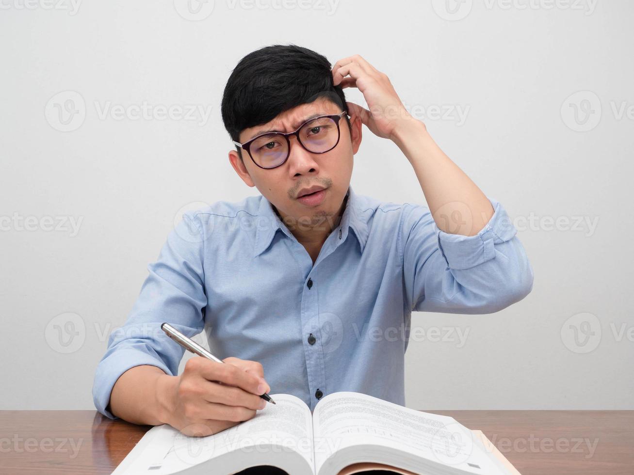Asian businessman sit at working table feels confused scratch head gesture doubt photo