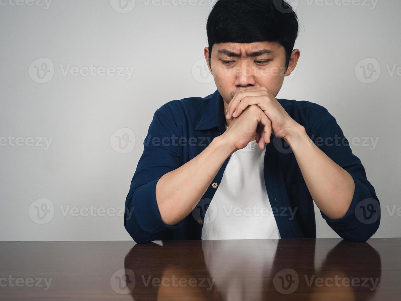 tristeza hombre asiático sentarse a la mesa deprimido emoción foto