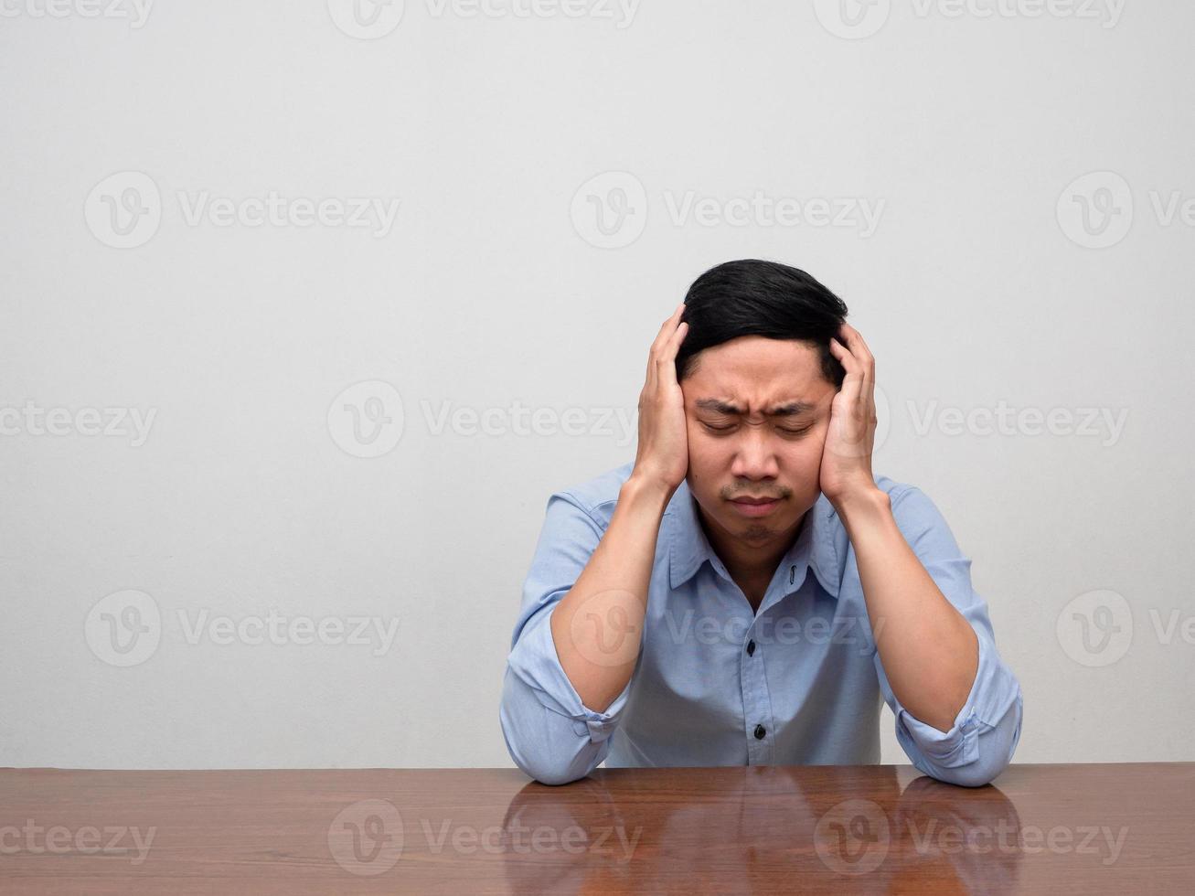 Asian man blue shirt sit loneliness at table feels tried and disheartened photo