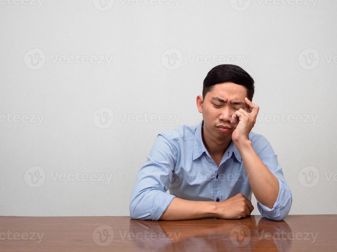Asian man blue shirt sit loneliness at table feels tried and disheartened photo
