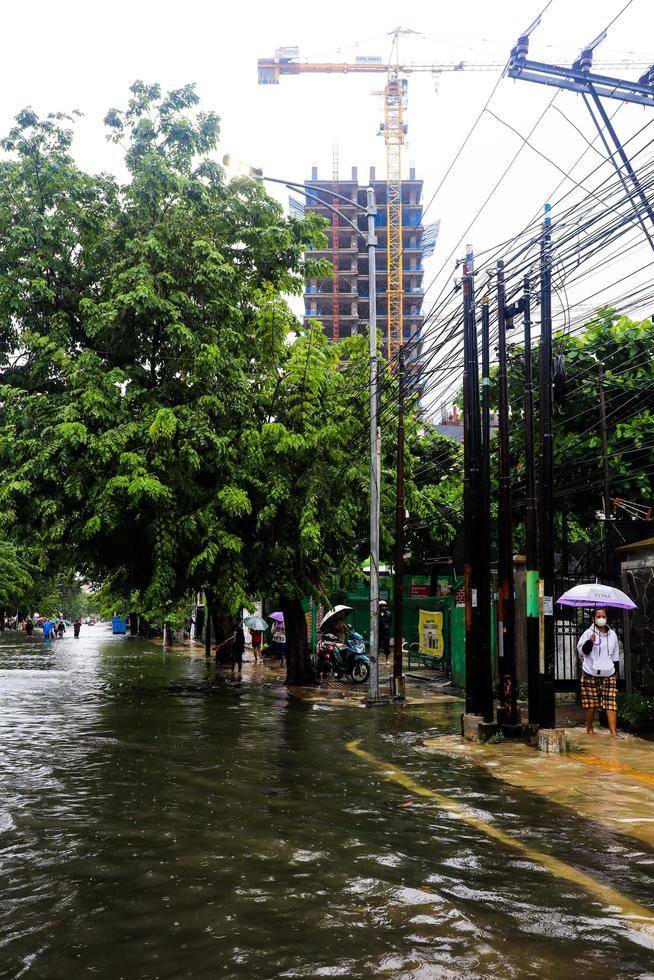 Semarang, December 2022. Some people are walking through the flood that hit the Poncol train station area and some residents are preparing to evacuate. vehicles hit the flood photo