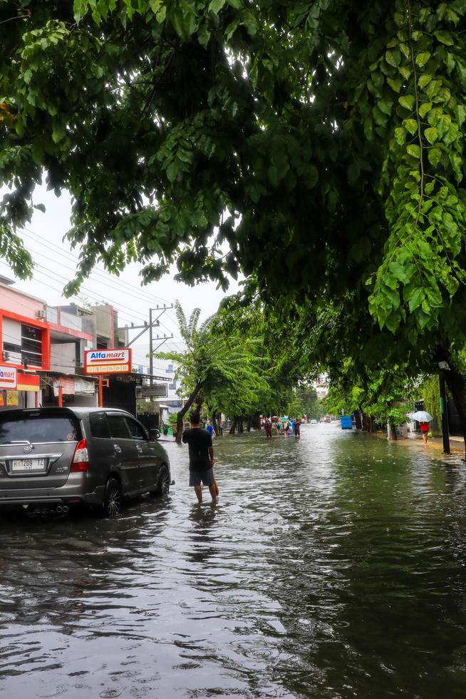 Semarang, December 2022. Some people are walking through the flood that hit the Poncol train station area and some residents are preparing to evacuate. vehicles hit the flood photo