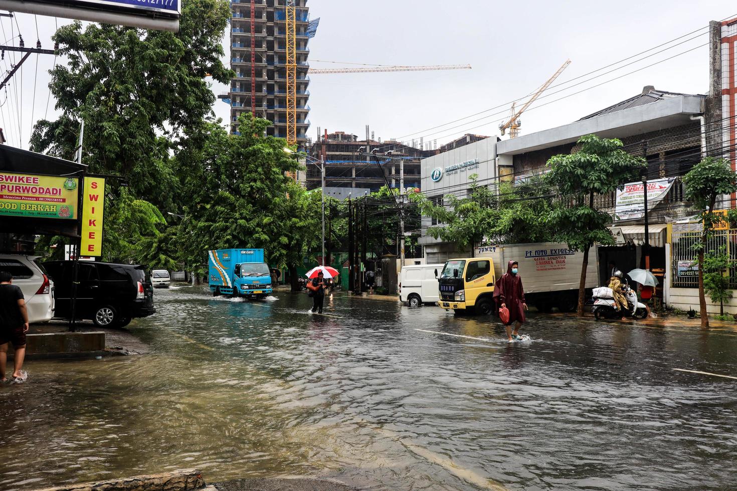 Semarang, December 2022. Some people are walking through the flood that hit the Poncol train station area and some residents are preparing to evacuate. vehicles hit the flood photo