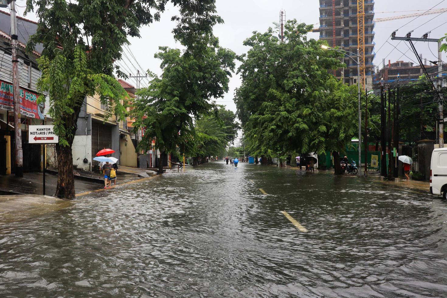 Semarang, December 2022. Some people are walking through the flood that hit the Poncol train station area and some residents are preparing to evacuate. vehicles hit the flood photo