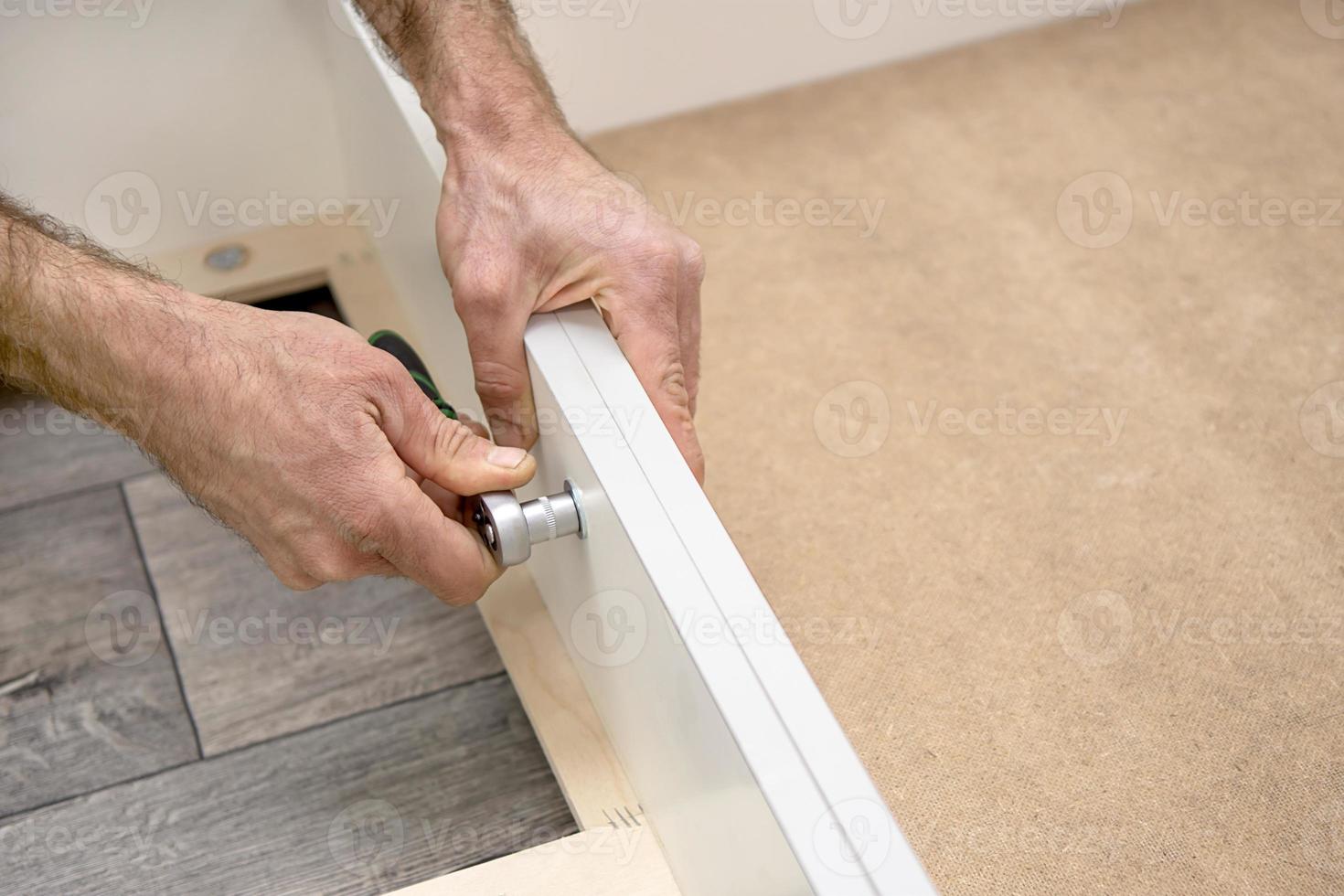 Workers assembling furniture at home. Hands tightening the bolt. photo