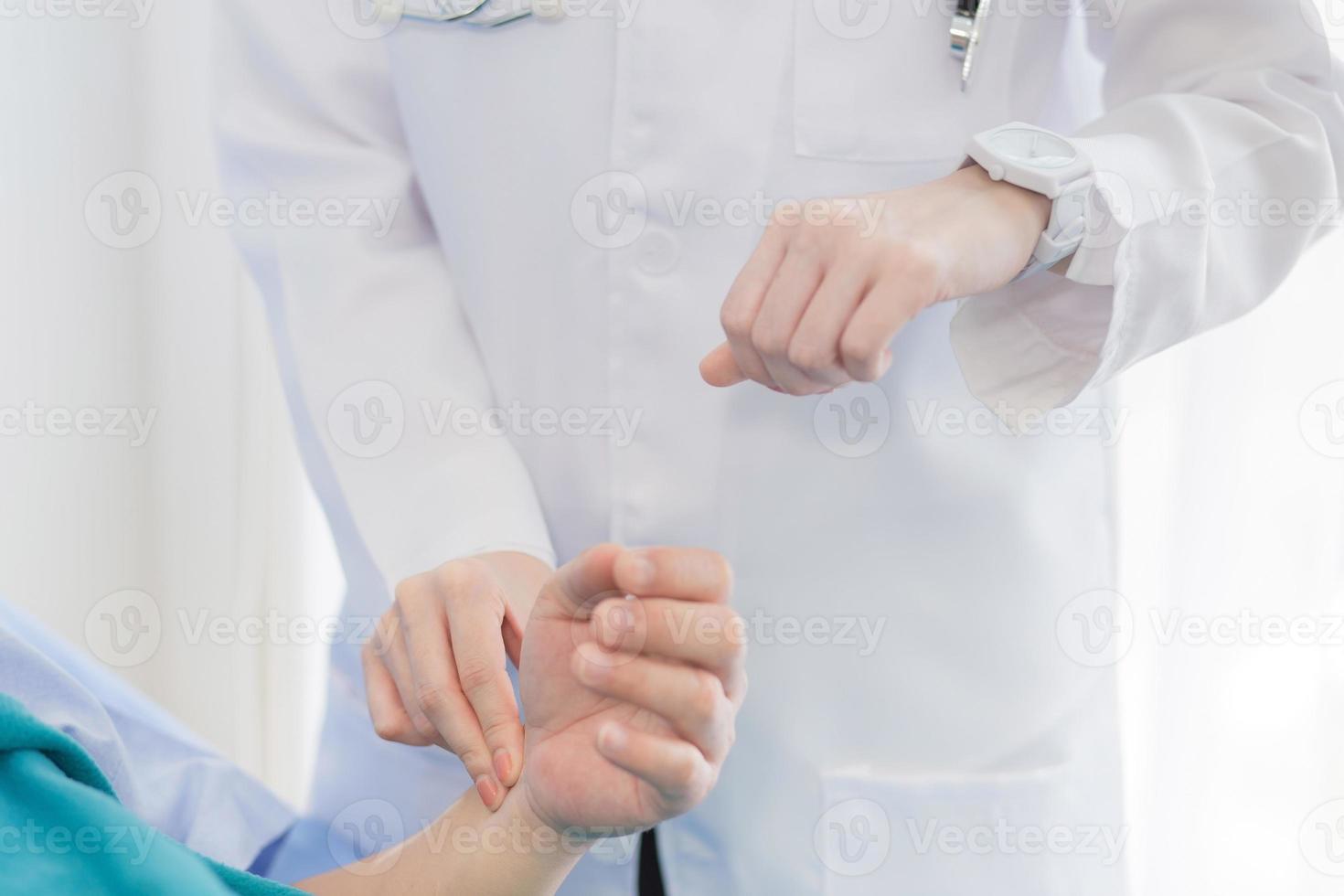 una doctora está tomando el pulso en la muñeca de un paciente hombre foto