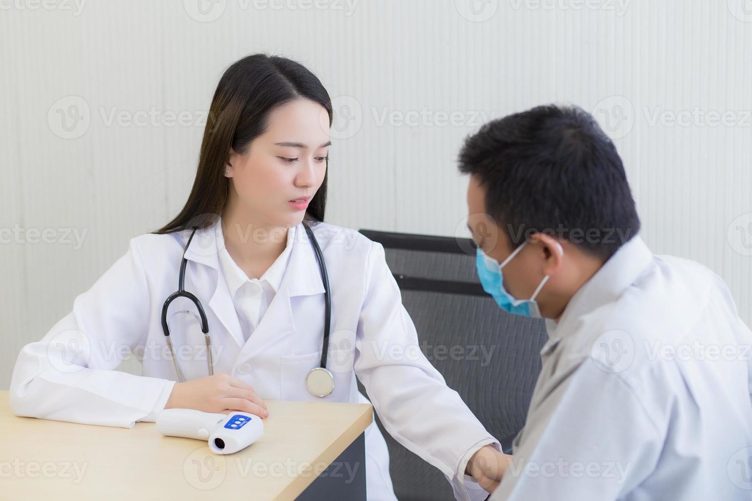 Hermosa joven asiática doctora hablando con un paciente hombre foto