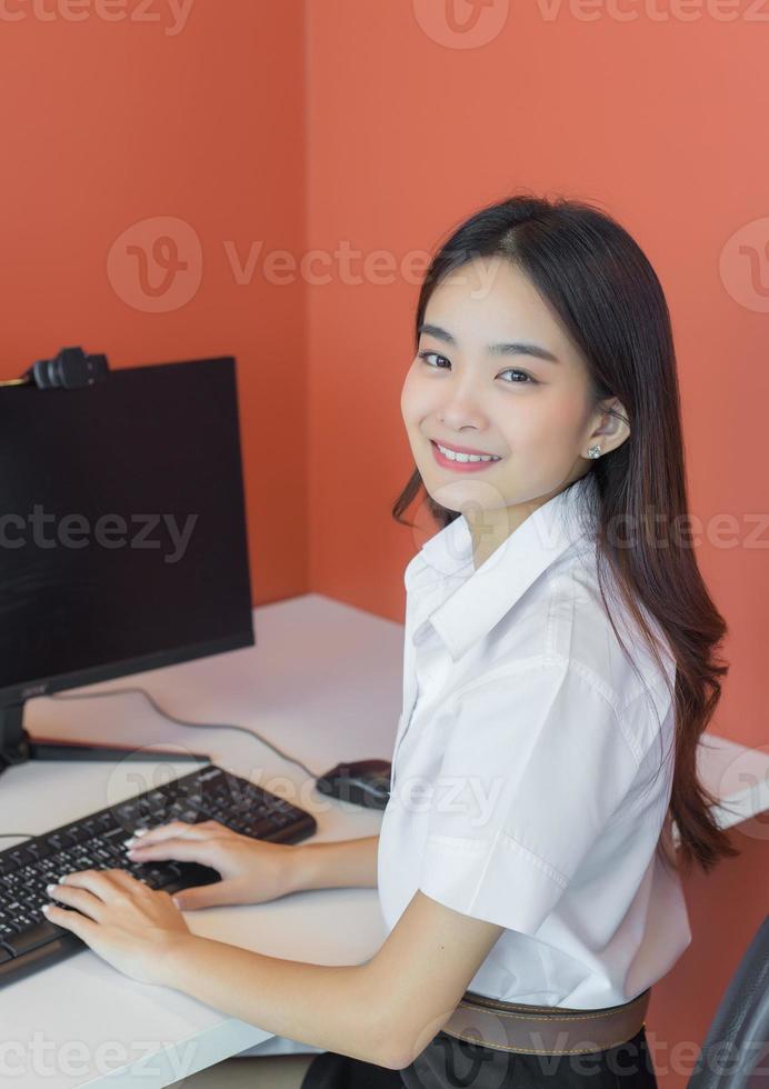 Young female students in uniform are using personal computers in the classroom in university. photo