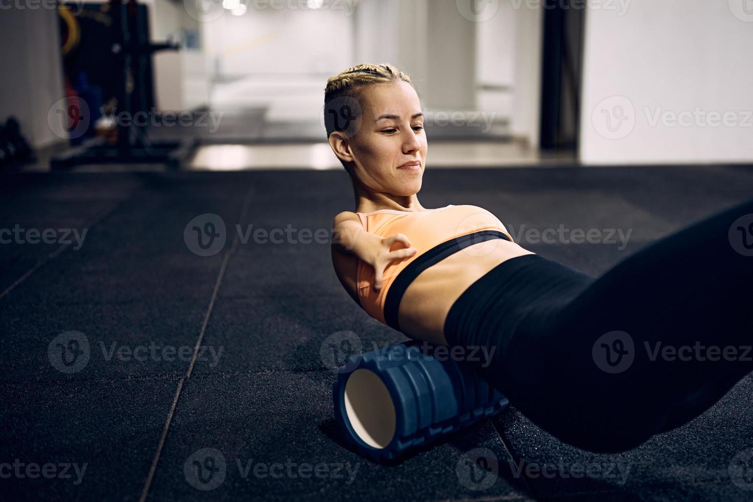 atleta sin brazos masajeando su espalda con un rodillo de espuma después de hacer ejercicio en un gimnasio. foto