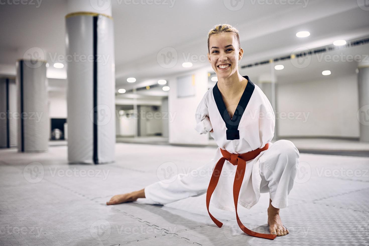 feliz deportista sin brazos practicando taekwondo en el club de artes marciales y mirando a la cámara. foto