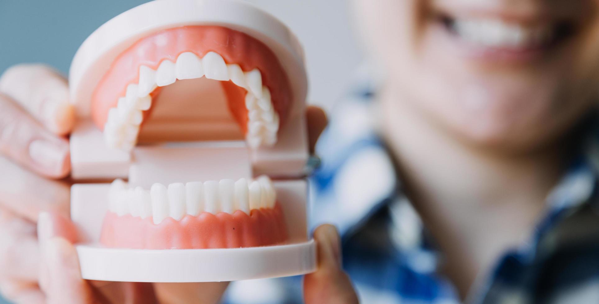 Stomatology concept, partial portrait of girl with strong white teeth looking at camera and smiling, fingers near face. Closeup of young woman at dentist's, studio, indoors photo