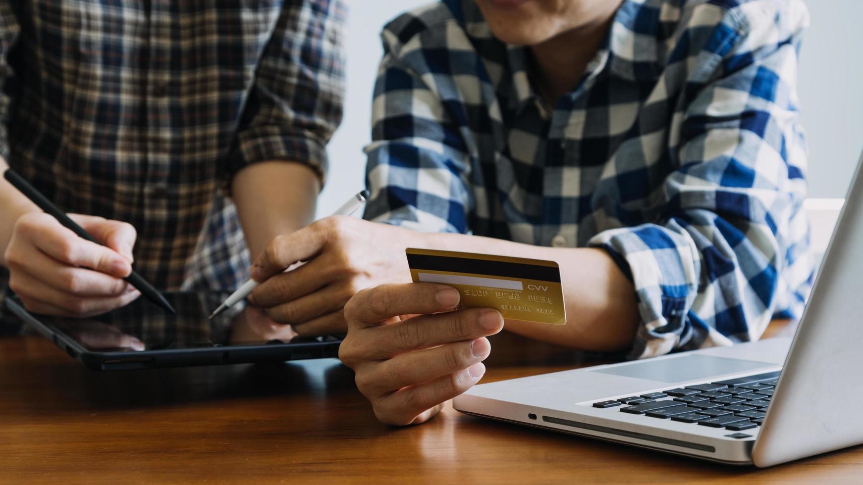 manos sosteniendo la tarjeta de crédito y usando la computadora portátil. las compras en línea foto