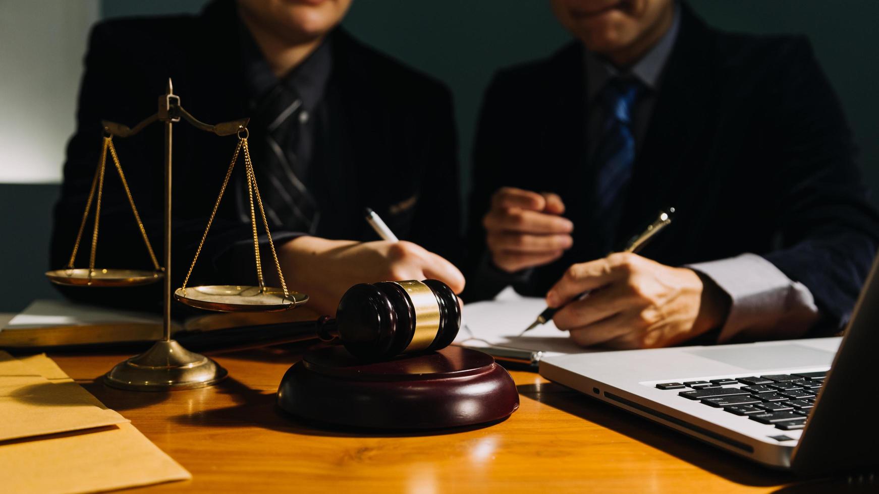 Business and lawyers discussing contract papers with brass scale on desk in office. Law, legal services, advice, justice and law concept picture with film grain effect photo