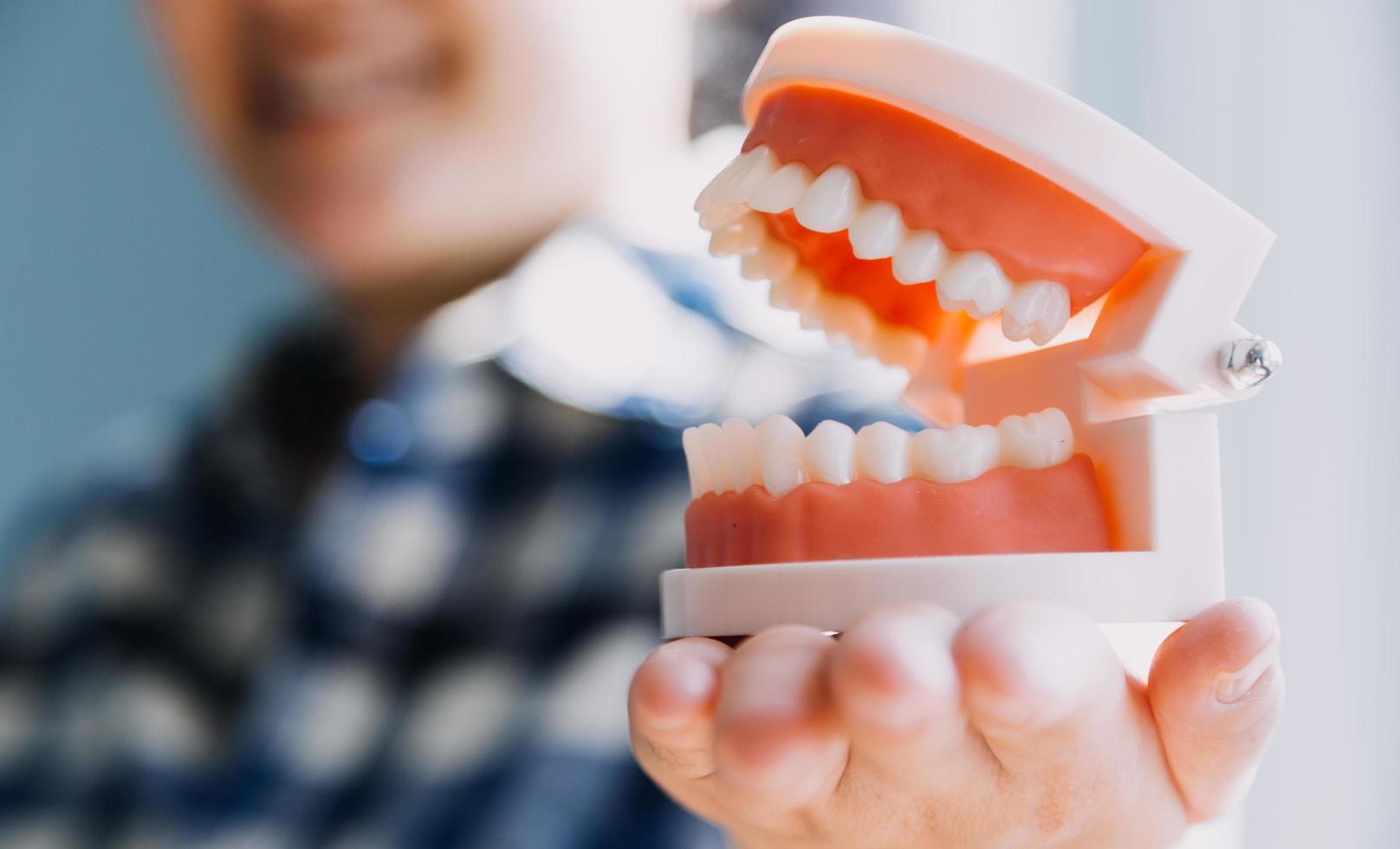 Stomatology concept, partial portrait of girl with strong white teeth looking at camera and smiling, fingers near face. Closeup of young woman at dentist's, studio, indoors photo