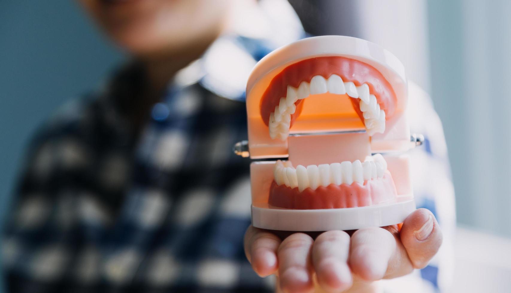 Stomatology concept, partial portrait of girl with strong white teeth looking at camera and smiling, fingers near face. Closeup of young woman at dentist's, studio, indoors photo