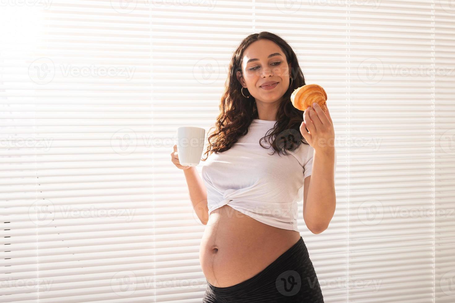 mujer embarazada feliz con bollos de croissant en casa. concepto de embarazo, alimentación y personas foto