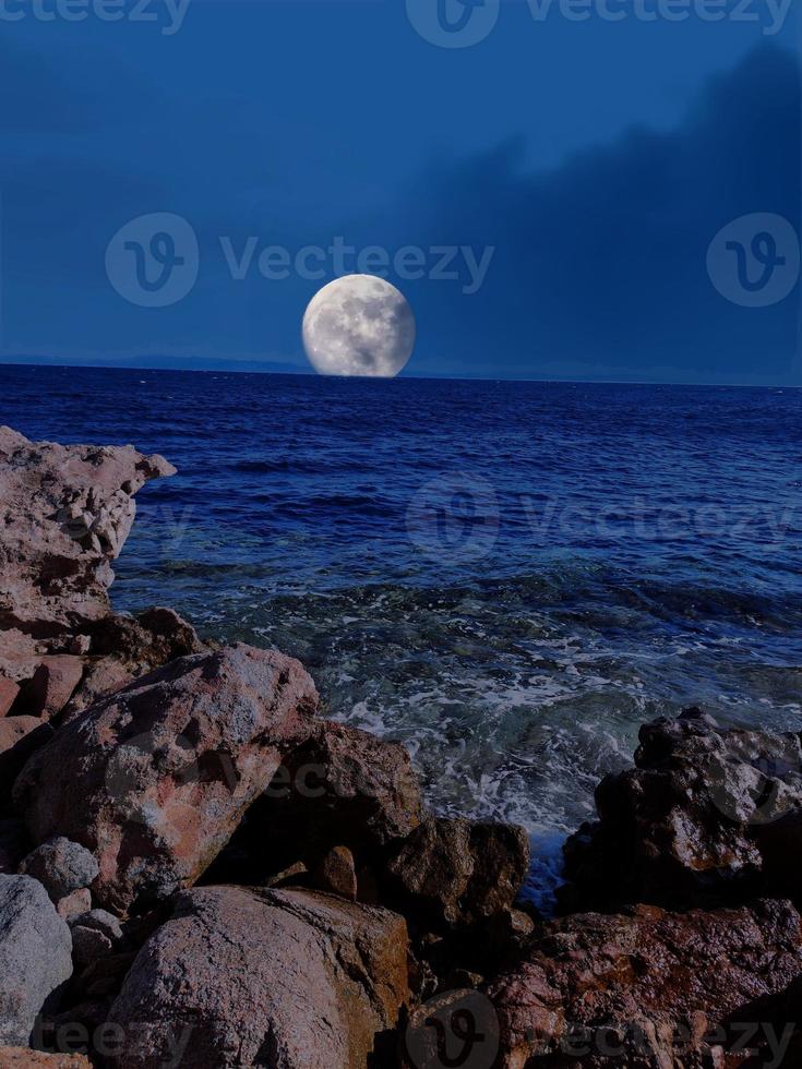 Scenic view of red sea at night with full moon above the sea and mountains photo