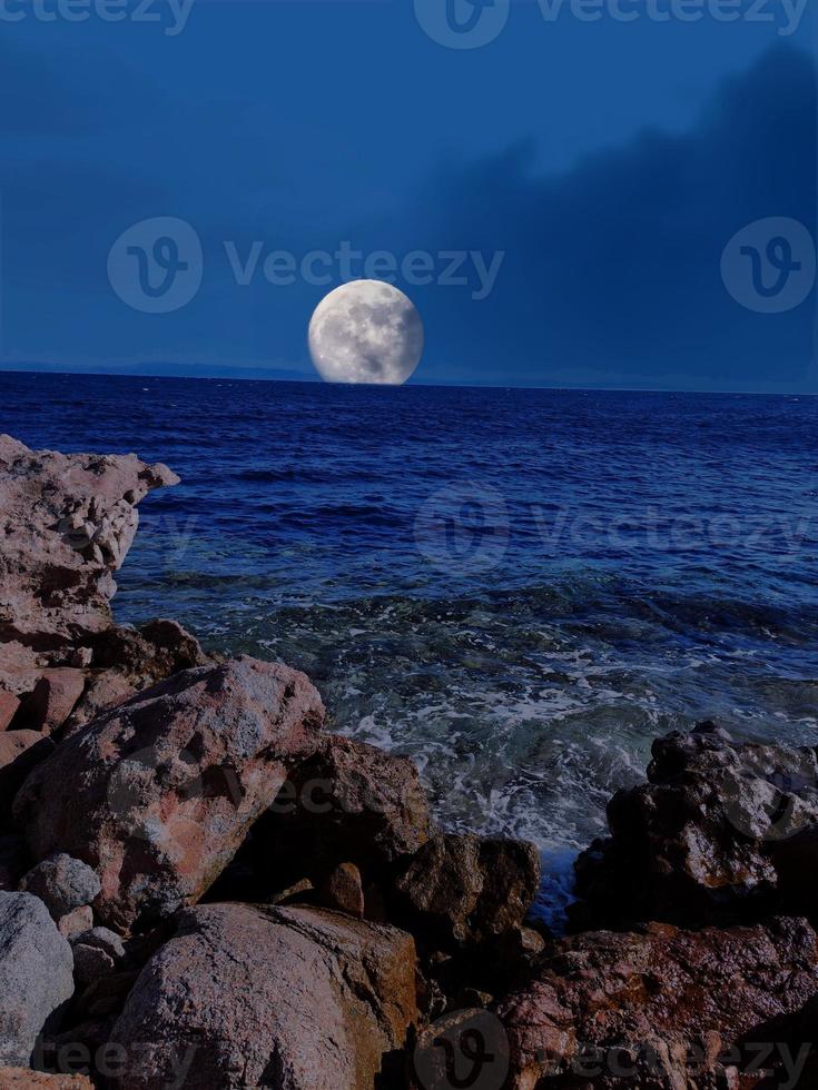 vista panorámica del mar rojo por la noche con luna llena sobre el mar y las montañas foto