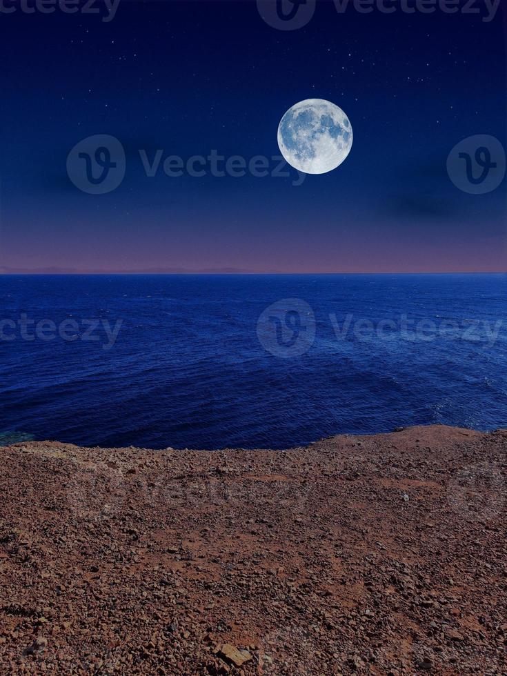 Scenic view of red sea at night with full moon above the sea and mountains photo