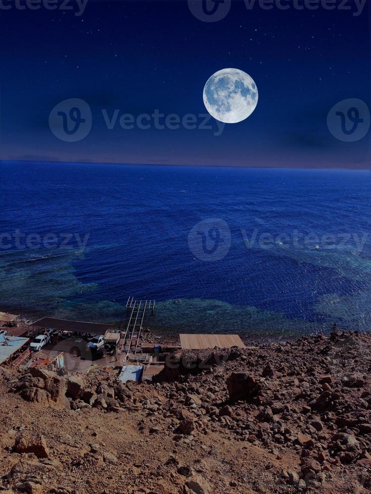 Scenic view of red sea at night with full moon above the sea and mountains photo