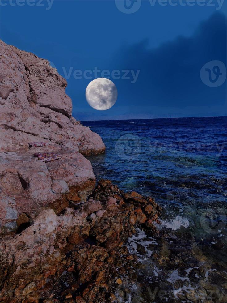 vista panorámica del mar rojo por la noche con luna llena sobre el mar y las montañas foto