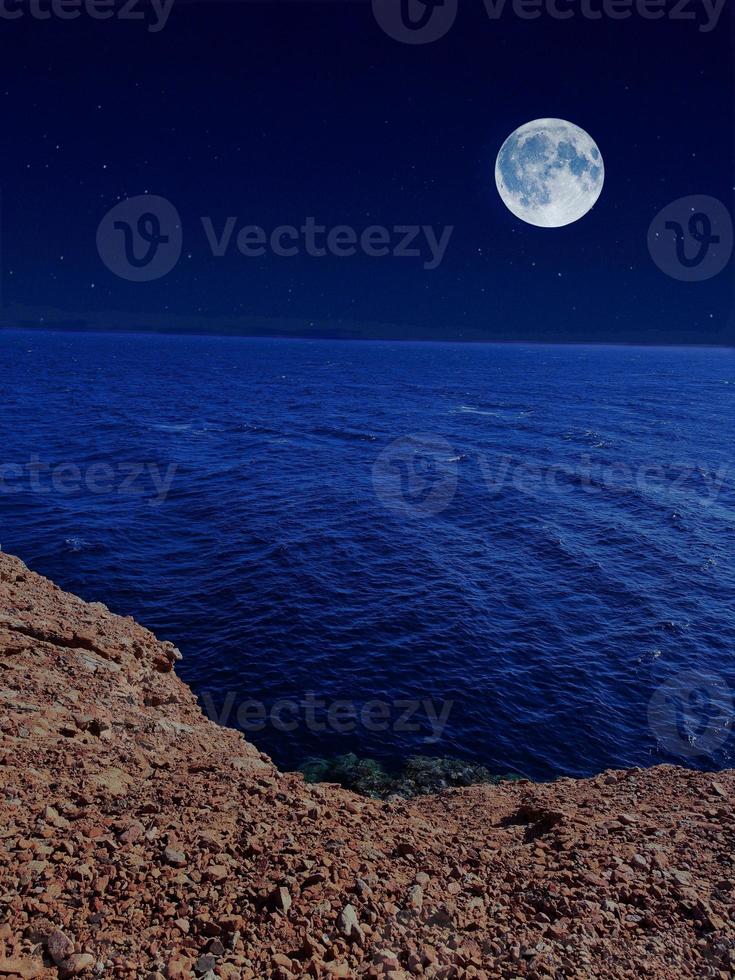 Scenic view of red sea at night with full moon above the sea and mountains photo