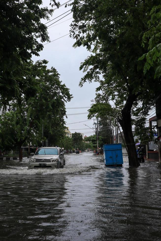 Semarang, December 2022. Some people are walking through the flood that hit the Poncol train station area and some residents are preparing to evacuate. vehicles hit the flood photo