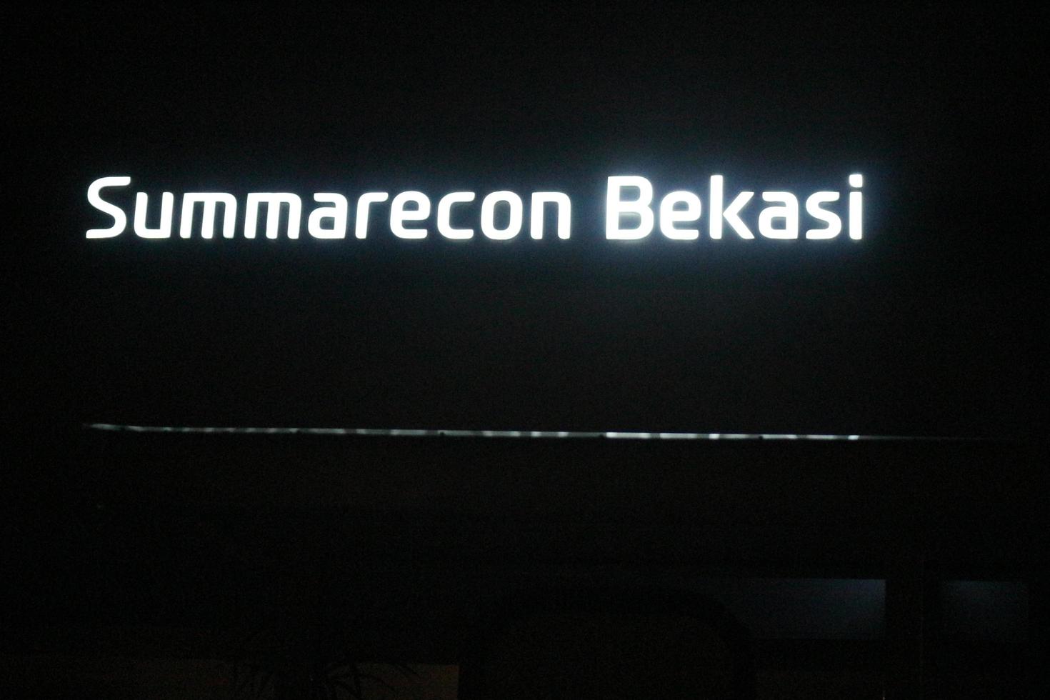 bekasi, indonesia en julio de 2022. el logotipo de summarecon bekasi brilla intensamente por la noche contra el oscuro cielo nocturno. foto