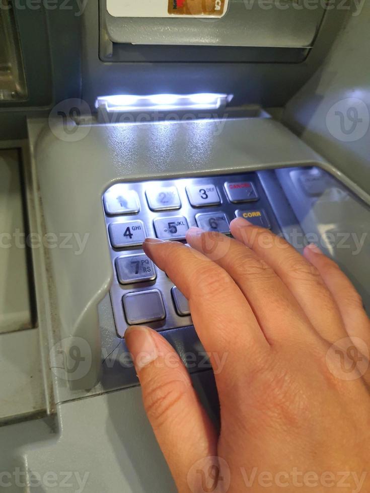 West Java, Indonesia in July 2022. A hand is pressing the numeric keypad on an ATM machine photo
