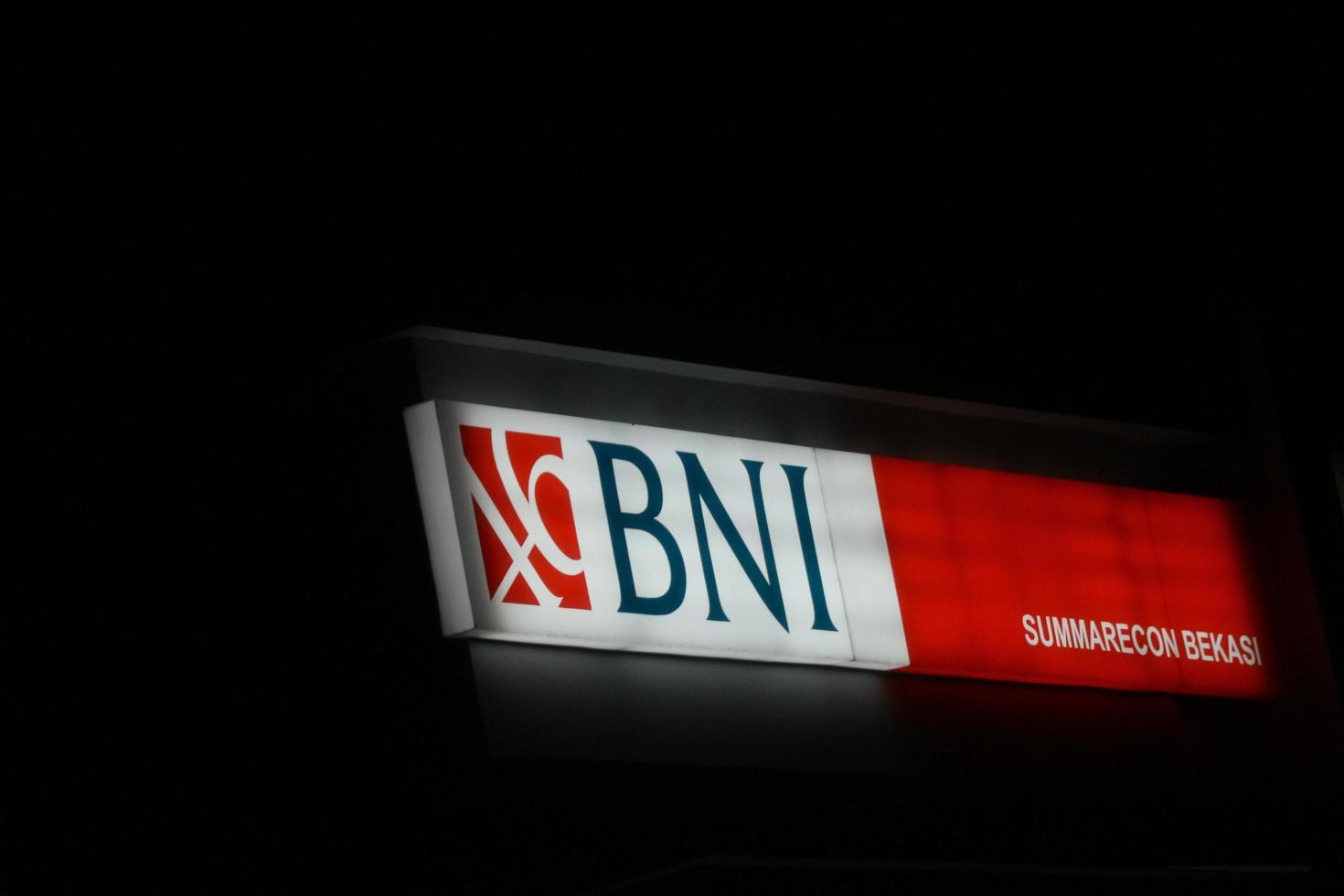 Bekasi, Indonesia in July 2022. Bank BNI's logo shining brightly at night against the dark night sky. photo