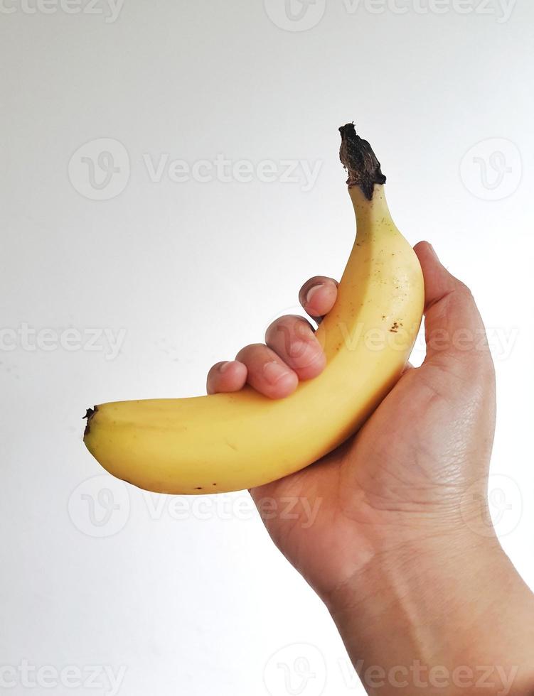foto blanca aislada de la mano de una mujer sosteniendo un plátano amarillo cavendish.