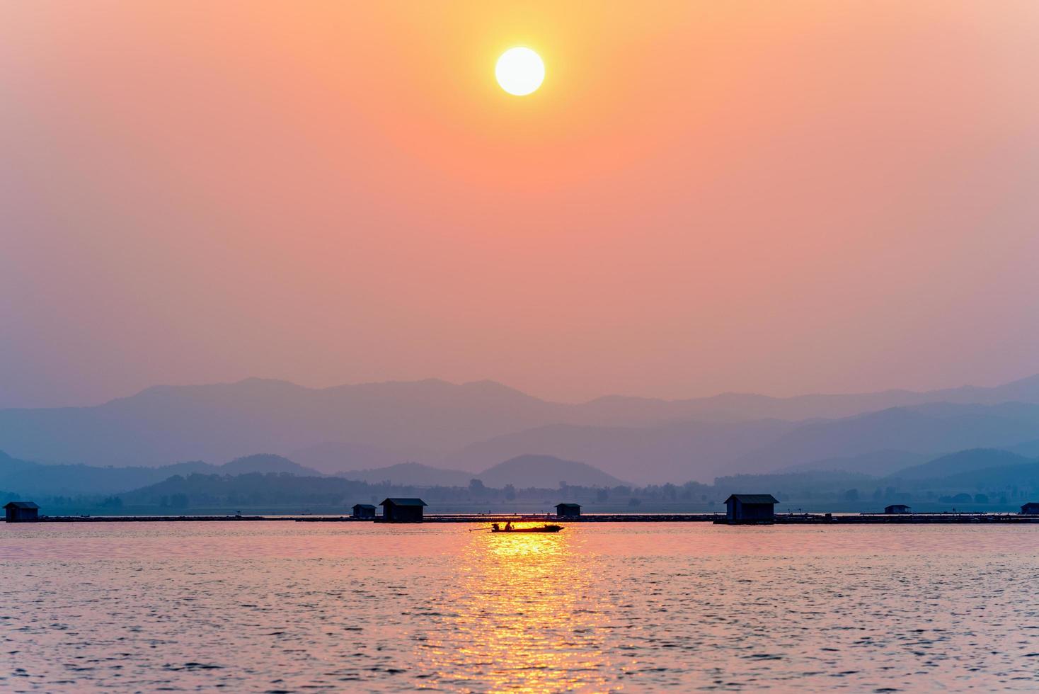 Fisherman driving a boat to home at sunset photo