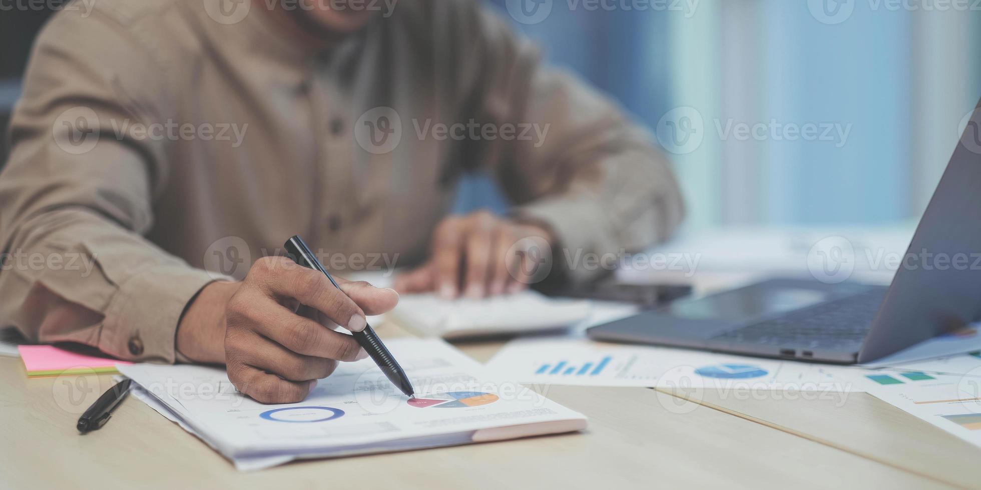Close-up of the hands of a businessman using a calculator to check financial accounts check the company's expenses and budget. photo