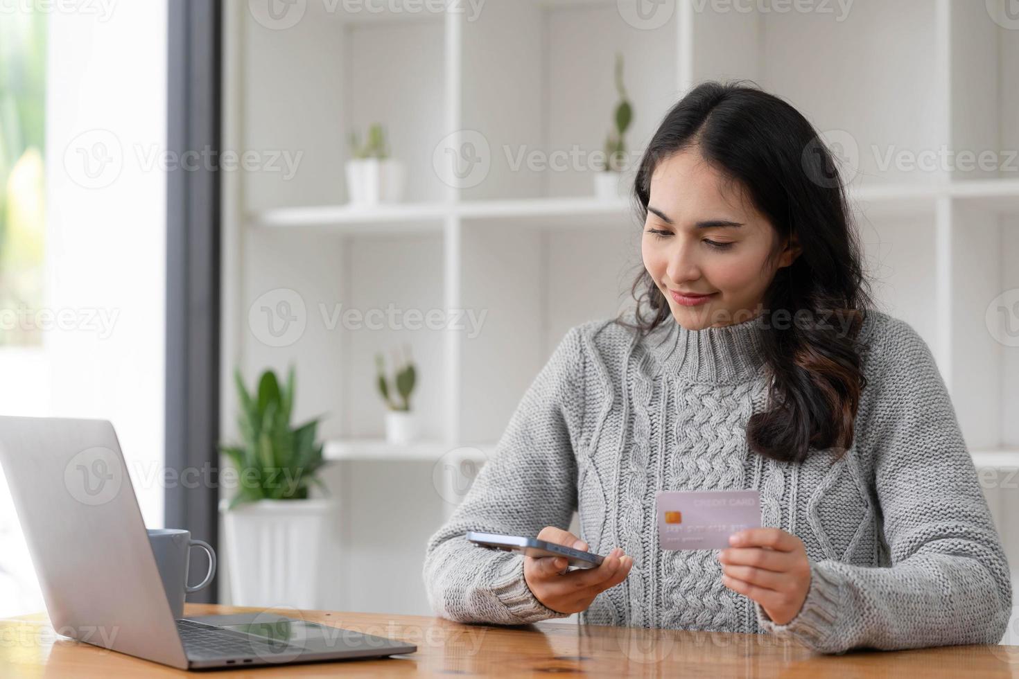 mujer de negocios asiática feliz paga en línea usando el teléfono móvil en la oficina. foto