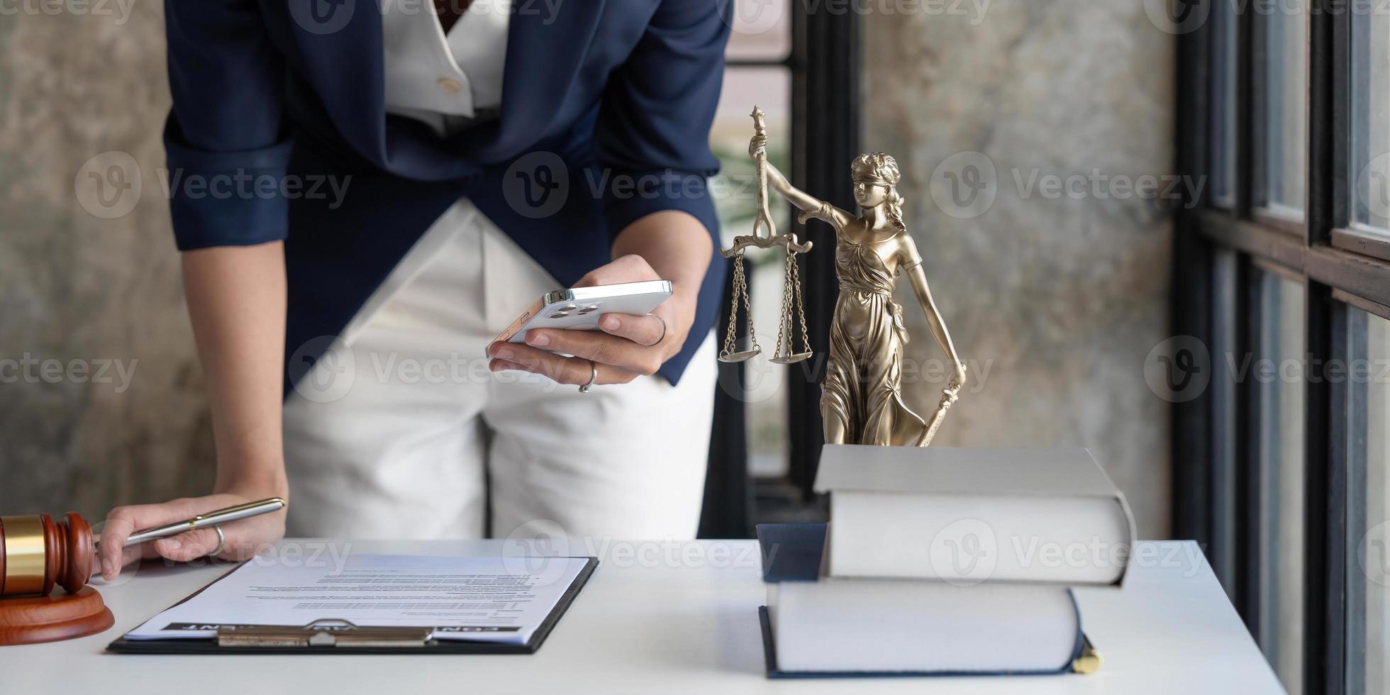 Attractive young lawyer or Businesswoman talking on phone and lawyers discussing contract papers with brass scale on wooden desk in office. Law, legal services, advice, Justice and real estate concept photo