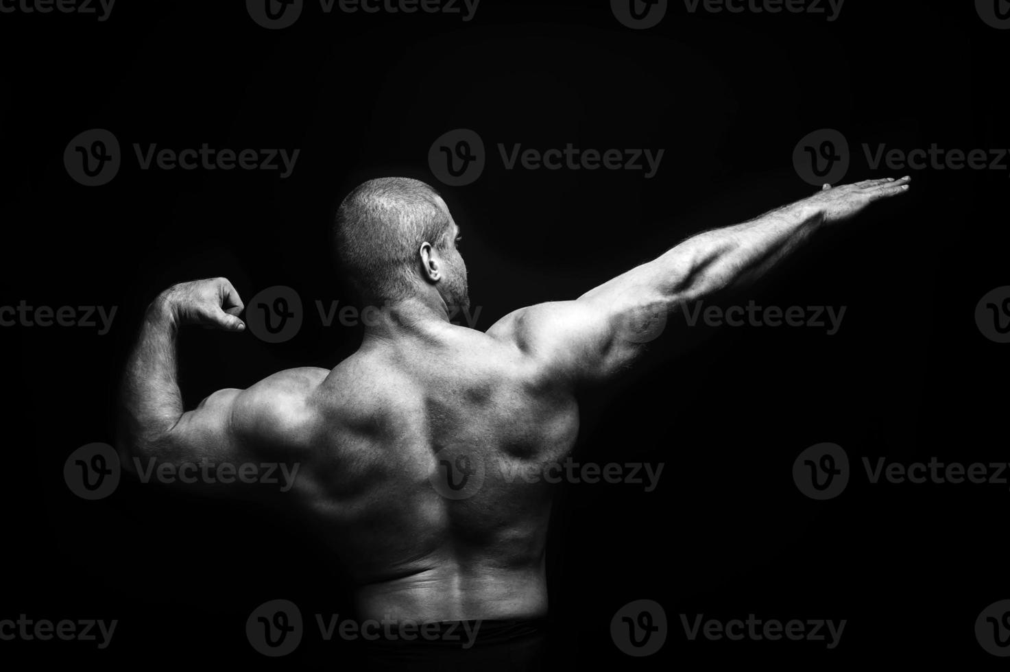 sports man standing on a black background, doing sports photo