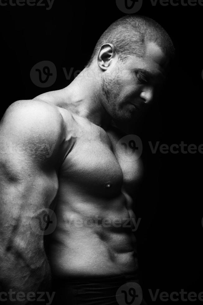 sports man standing on a black background, doing sports photo