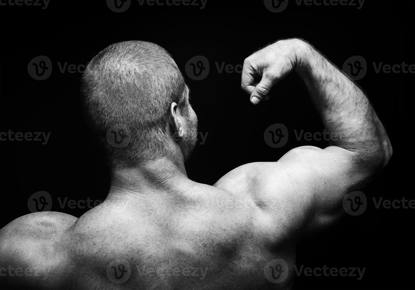 sports man standing on a black background, doing sports photo